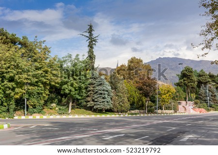 Winter Tehran street view in Tehran International Exhibition Center with snow covered Alborz Mountains against cloudy sky on background