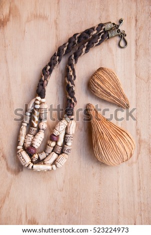 Tribal african bone beads with decor nature element on wooden background.