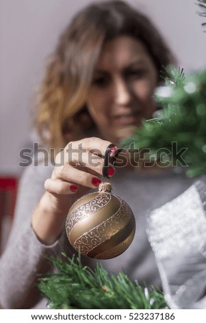 picture of woman decorating christmas tree with balls and santa