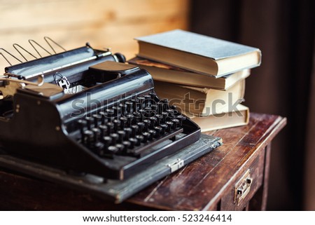 vintage typewriter and books on the table with blank paper on wooden desk Royalty-Free Stock Photo #523246414