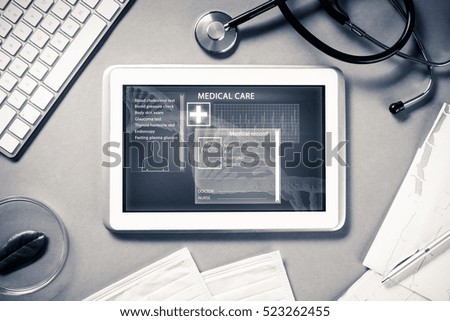 White tablet pc and doctor tools on gray surface