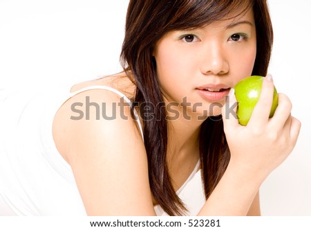 A pretty young asian woman in white eating an apple