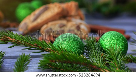 Christmas background with fir branches. Green spruce branch with green Christmas toys. Biscotti, cantuccini, cinnamon.