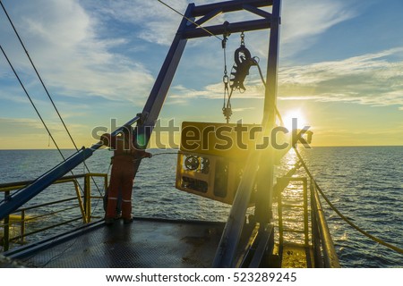  worker recovering robotics Remote Operated Vehicle (ROV) after entering sea surface during oil and gas pipeline inspection in the middle of South China Sea isolated on sunrise with glare Royalty-Free Stock Photo #523289245