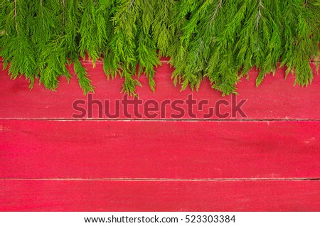 Christmas tree garland border on antique red rustic wood background; Christmas background with red copy space