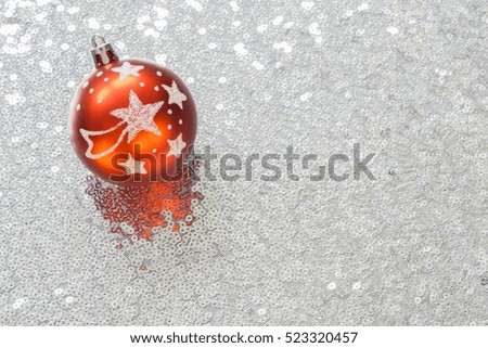 Christmas decorations on silver fabric with sequins, a Christmas ball with stars and a shooting star in the upper left corner, copy space