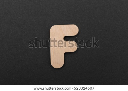 F. English alphabet made of wood are isolated on a black background. Latin.