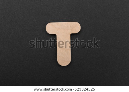 T. English alphabet made of wood are isolated on a black background. Latin.
