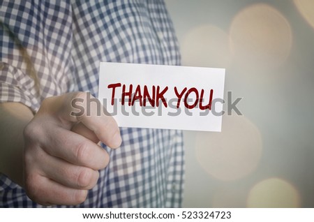 Man showing Thank You card. Blurred bokeh background. 