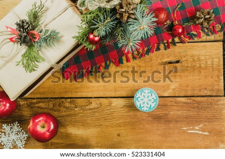 Still life on the theme of Christmas . on the table toys - balls are red , the bouquet fir branches , gift box , American flag , apples ,  a list of Santa Claus ,hourglass