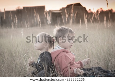 Little children sit in the field at sunset