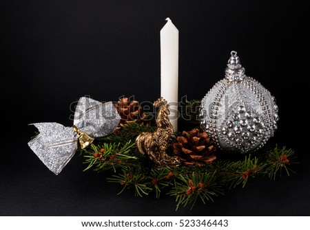Christmas or New Year decoration background: fur-tree branches, cones, ball, rooster, candle on black background