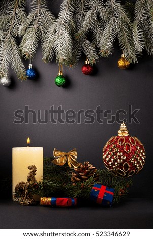 Christmas or New Year decoration background: fur-tree branches, cones, balls, candle, presents and snoflakes on black background