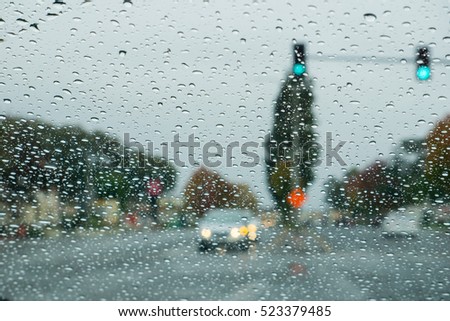 Raindrops on the windshield on a rainy day, traffic light background, California