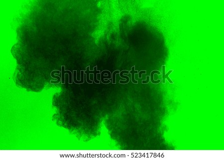 particles of charcoal on green background,abstract powder splatted background,Freeze motion of black powder exploding or throwing black powder.
