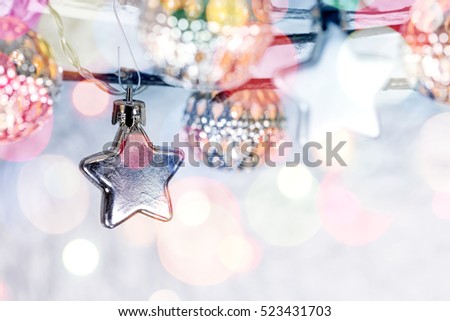 christmas star decorations and holiday lights hanging on blurred silver background