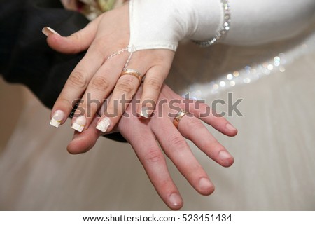 bride and groom show their hands wearing wedding rings