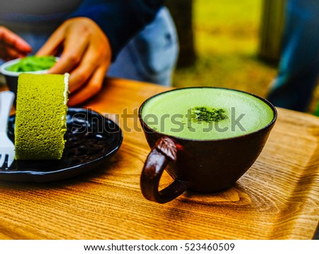 Green tea roll cake and green tea latte coffee in green tea shop at Osulloc tea museum, Jeju island, South Korea. Royalty-Free Stock Photo #523460509