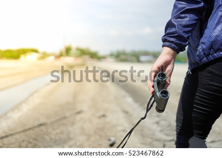 Asian woman's hand holding binoculars in the field outdoor, Technology Binoculars Scope background concept 