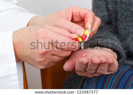 Close up picture of a doctor hand giving pills to a senior woman