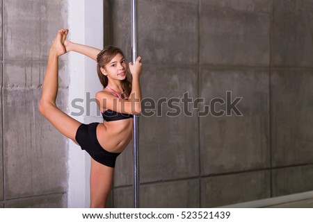 Pretty pole dancer girl working out in the studio