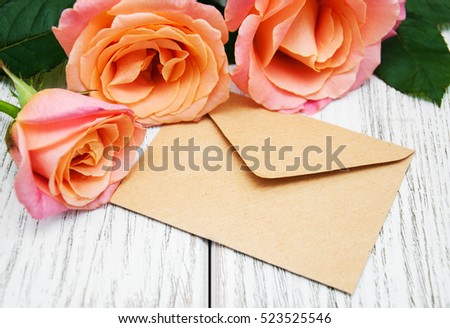 Pink roses and envelope on a old wooden background