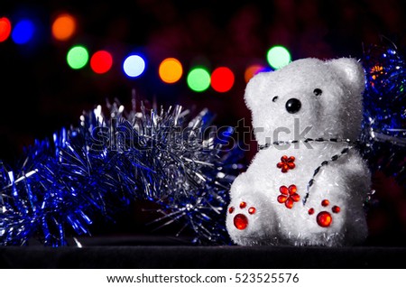 New Year's bear and tinsel at the Christmas garland background