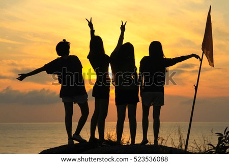 Silhouette of girl group in the morning at the beach waiting for the sunrise.