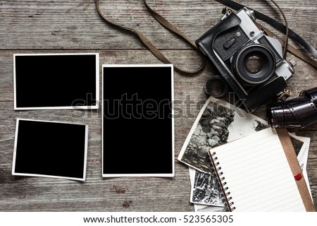 vintage retro camera on wood table background with blanks photos to placed your pictures and notebook.