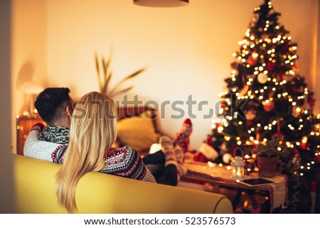 Rear view of a couple sitting on a sofa and looking at Christmas tree.