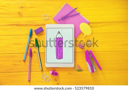 Colourful stationery and tablet on yellow wooden background