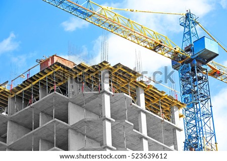 Crane and building under construction against blue sky Royalty-Free Stock Photo #523639612