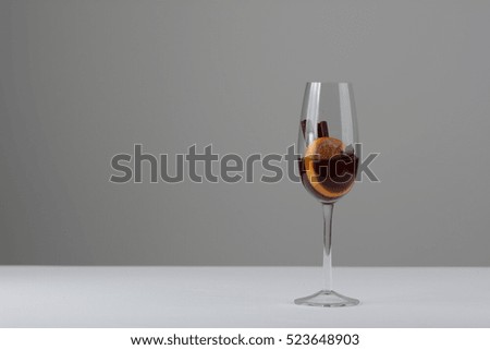 Red wine glass isolated on a white and grey background. Cinnamon sticks, star anise and orange. Christmas mulled wine. Mulled wine with spices. Studio photography. Celebrating love. 