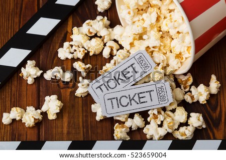 Clapper board, spilled popcorn and movie tickets on a background of boards Royalty-Free Stock Photo #523659004
