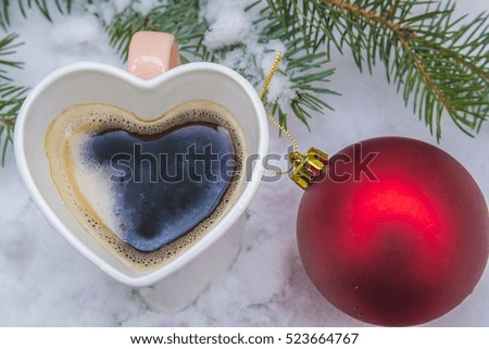 Christmas composition with coffee cup and red christmas ball on white snow background top view