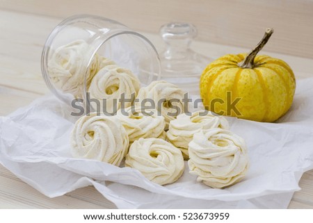 Yellow marshmallow in glass jar and pumpkin on white paper, selective focus