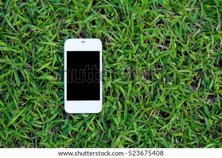 Mobile smart phones on green grass background. top view