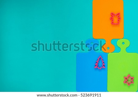 Kitchen art. Pattern from colored cutting boards and forms for baking on the edge of a wooden turquoise background. Abstract pattern. Copy space.