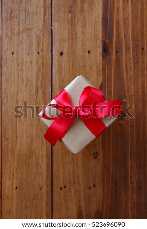 Gift box with red bow on a wooden table background