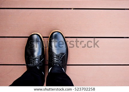 Businessman standing on the wooden floor in black man leather shoe on wooden background