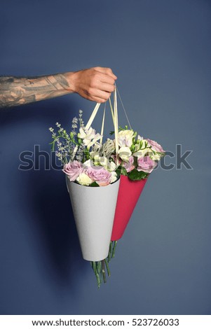 Male hand holding beautiful bouquets on color background