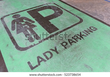 Car parking area available for lady with green color background on outdoor concrete floor at night time.