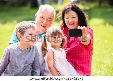 Happy Family Taking Selfie With Phone In Park