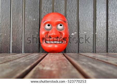 Japanese theater masks made of wooden on brown wood background,red mask