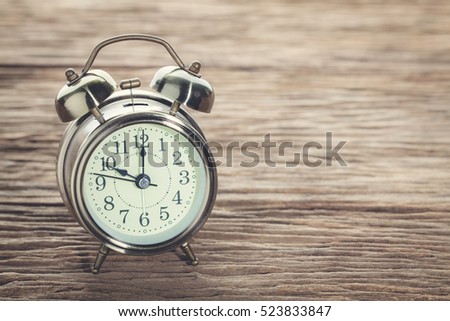 Clock at 10 O'clock in the morning with vintage style alarm clock on a wooden table.