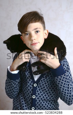 preteen handsome boy hold black cat on shoulders close up portrait