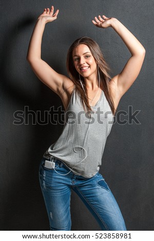 Brunette female against a black background playing with her mobile phone