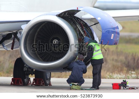 Technicians checking jet engine of civil airplane. Royalty-Free Stock Photo #523873930
