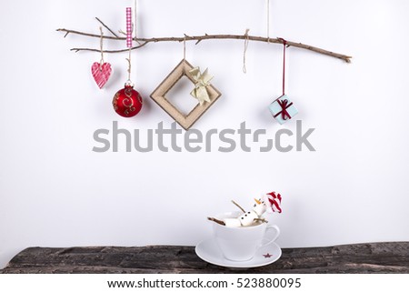 Marshmallow snowman fall down from the Christmas branch into the cup of coffee on white background