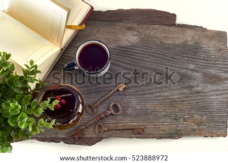 Old vintage books and cup with tea, cake and keys on table on rustic wooden background